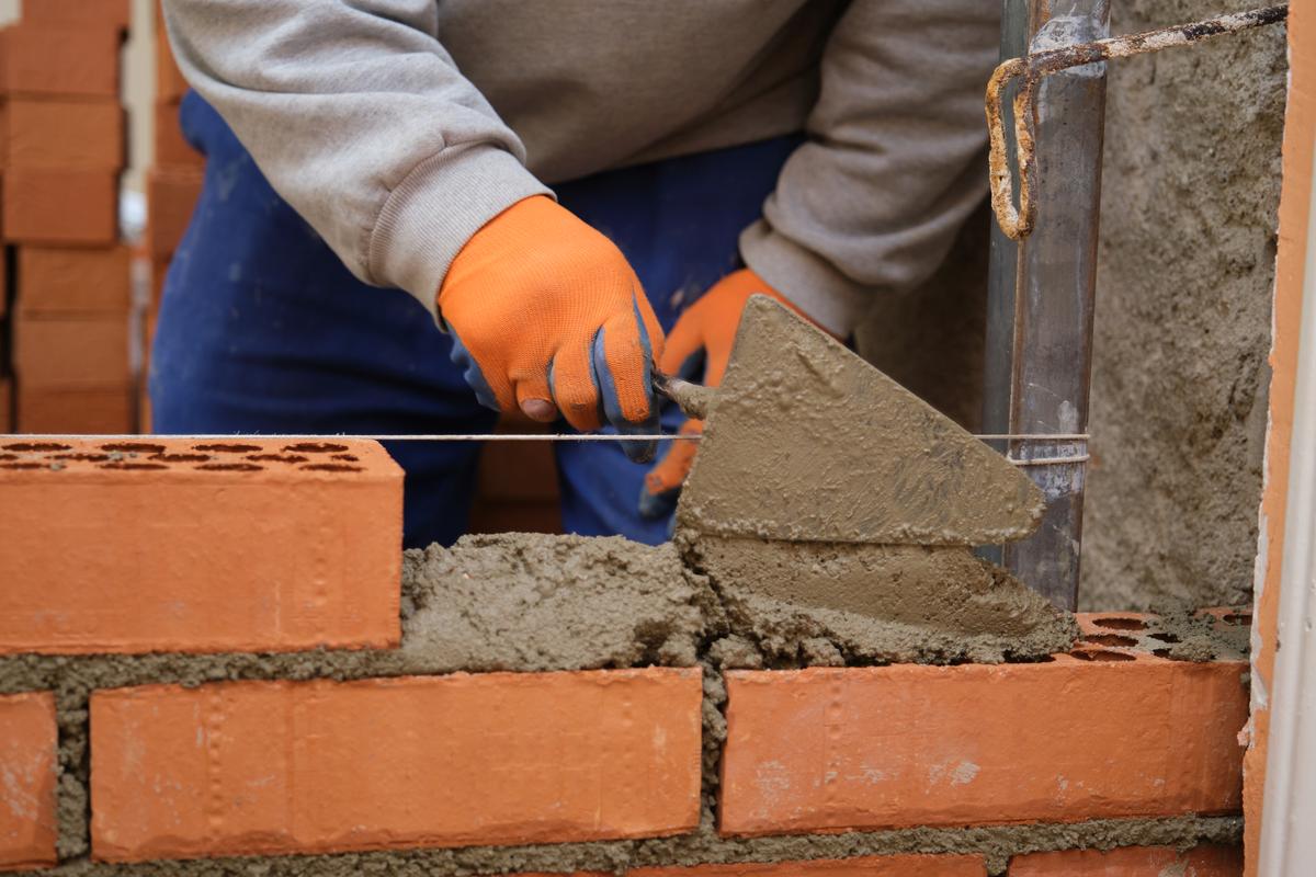Zedník pokládající cement mezi cihly